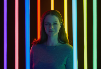 Liz West with neon lighting behind her